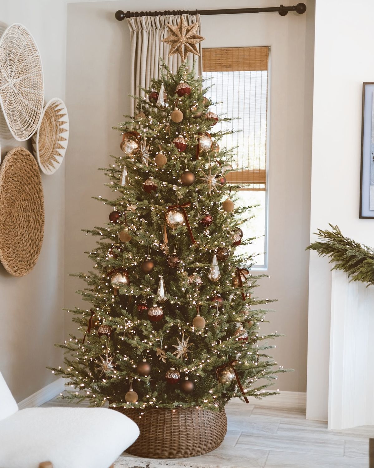 Christmas tree with a rustic woven tree collar, warm bronze and gold ornaments, and neutral holiday decor in a cozy living room.