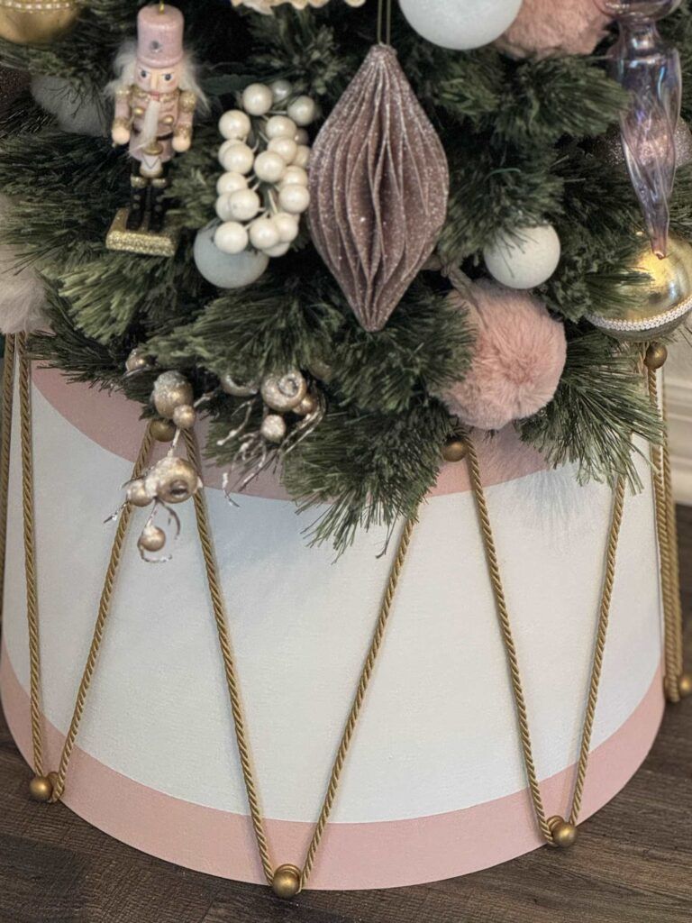 DIY drum-style Christmas tree collar with pink and white stripes and gold rope details for a creative handmade holiday decor idea.