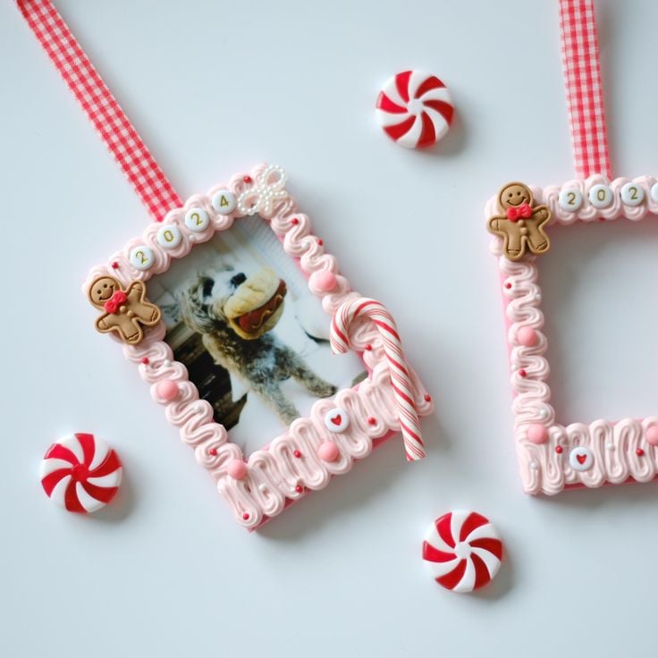 DIY candy-inspired whipped clay photo ornament decorated with pink frosting-like clay, candy canes, and gingerbread embellishments on a red gingham ribbon