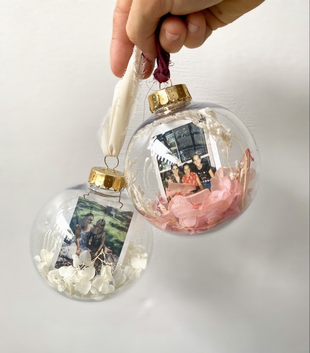 DIY clear glass photo ornaments filled with family photos, dried flowers, and gold caps tied with soft ribbon