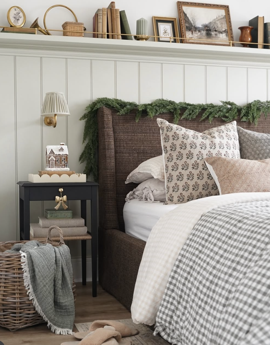 cozy farmhouse christmas bedroom with garland over headboard, vintage books, and neutral bedding