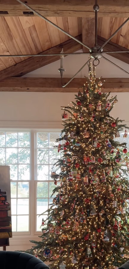cozy farmhouse Christmas tree with vintage colorful ornaments and warm white lights in rustic living room with wood-beamed ceiling