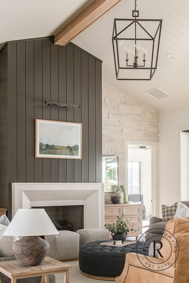 Modern farmhouse living room with dark green vertical shiplap fireplace wall, wood ceiling beam, landscape art, and white mantel.