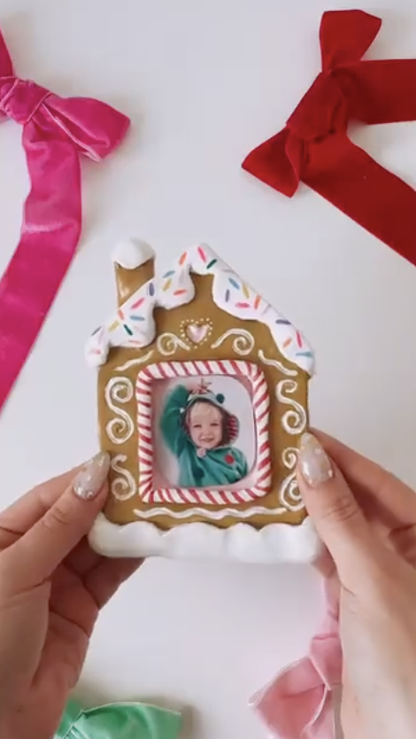 DIY clay gingerbread house photo ornament with icing details, sprinkles, and a child's photo in the center surrounded by colorful velvet ribbons