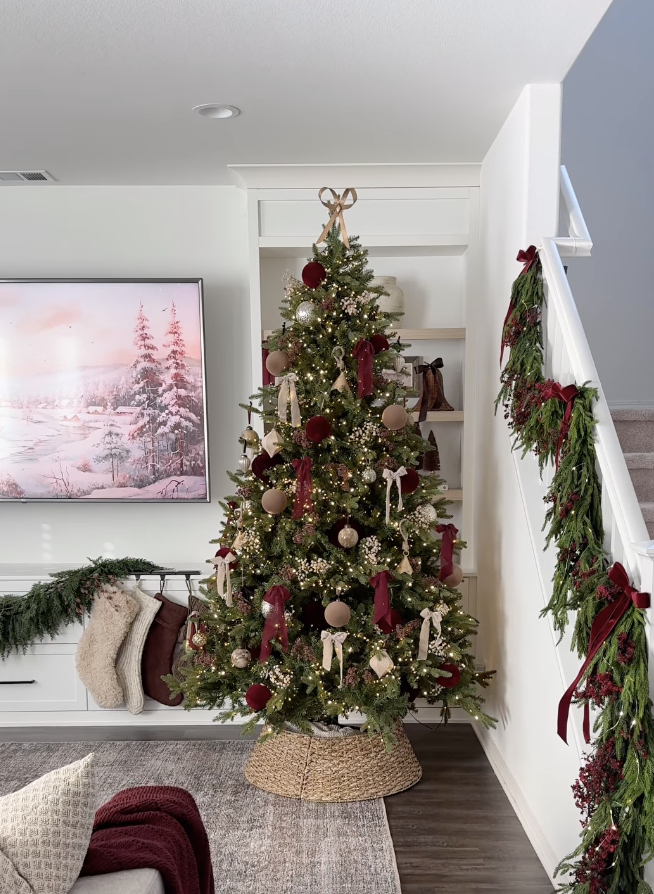 farmhouse Christmas tree with burgundy ribbons, neutral ornaments, and wicker basket base in cozy living room holiday decor