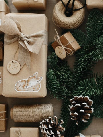 Farmhouse DIY advent calendar with kraft paper, wooden tags, pinecones, and greenery.