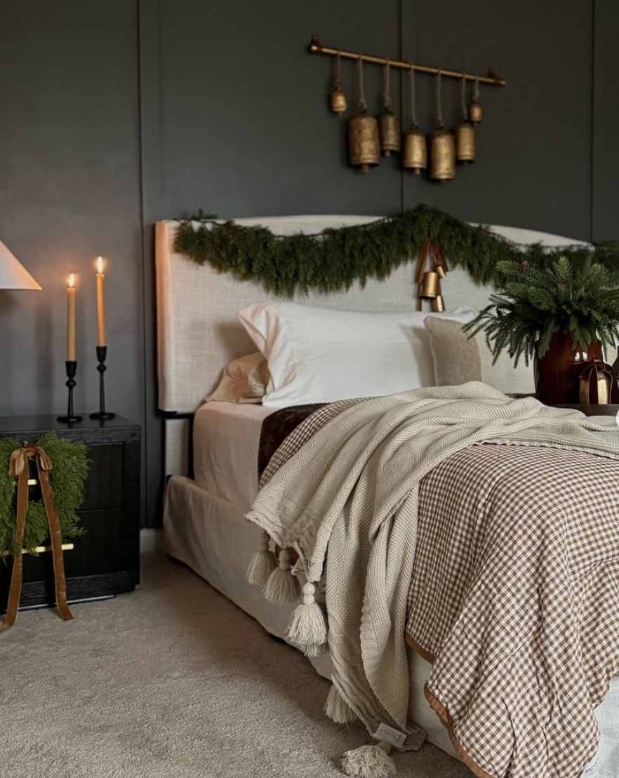 modern farmhouse christmas bedroom with dark walls, brass bells, greenery garland, and cozy neutral bedding