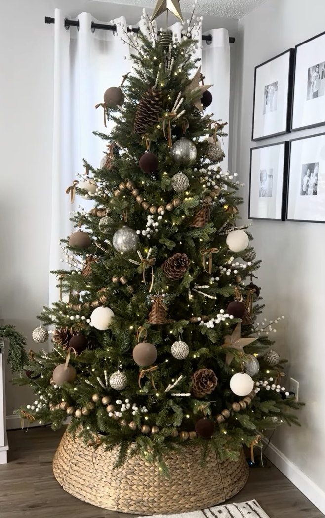 modern farmhouse Christmas tree with neutral brown and white ornaments, pinecones, and wood bead garland in cozy living room with woven tree collar