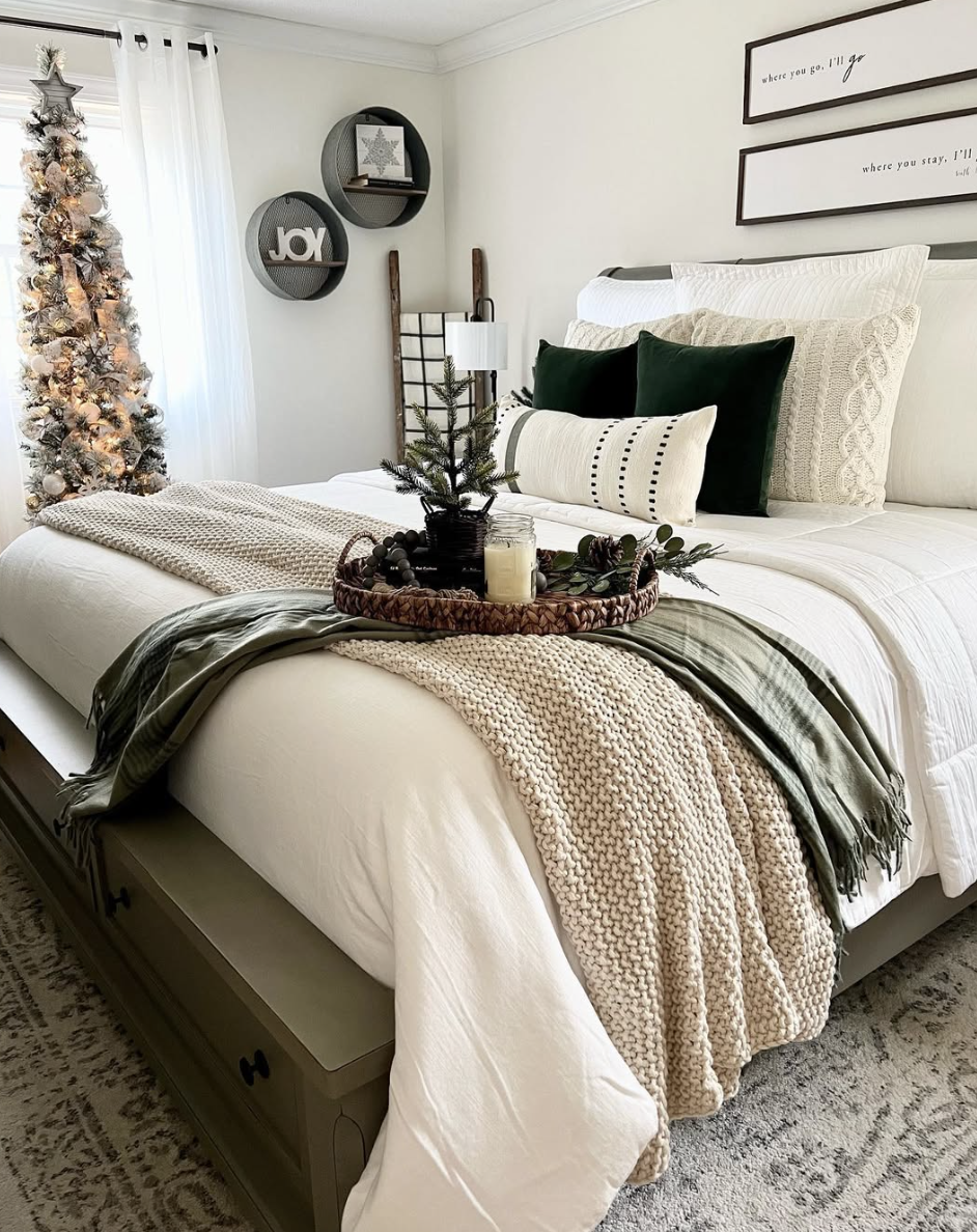 neutral farmhouse christmas bedroom with green pillows, cozy knit blankets, and frosted christmas tree