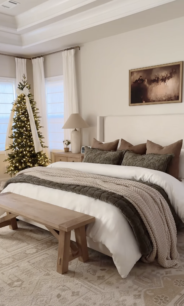 neutral farmhouse christmas bedroom with soft lighting, warm beige bedding, and simple christmas tree with white ribbon