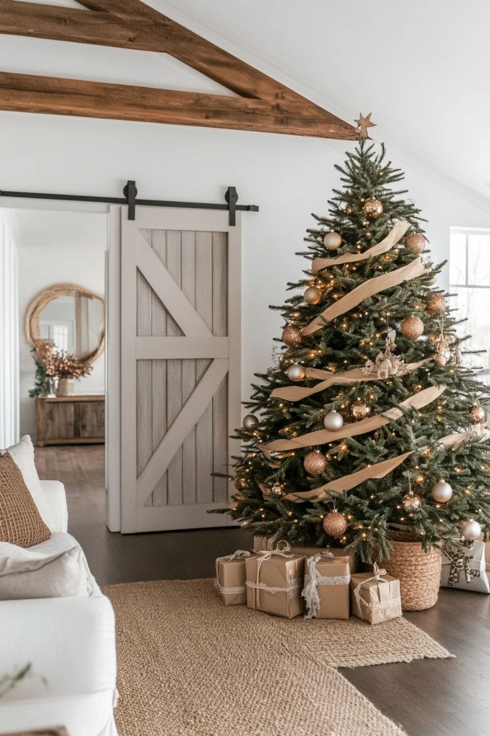 neutral modern farmhouse Christmas tree with burlap ribbon, gold ornaments, and kraft-wrapped gifts in cozy living room with barn door decor