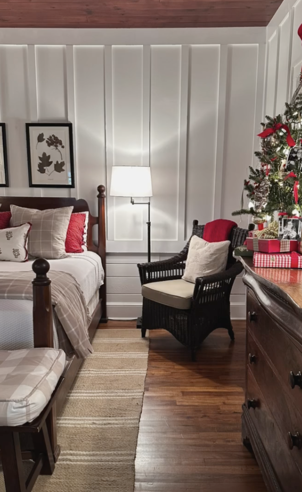 red and white farmhouse christmas bedroom with plaid pillows, wooden furniture, and small christmas tree with red ribbons