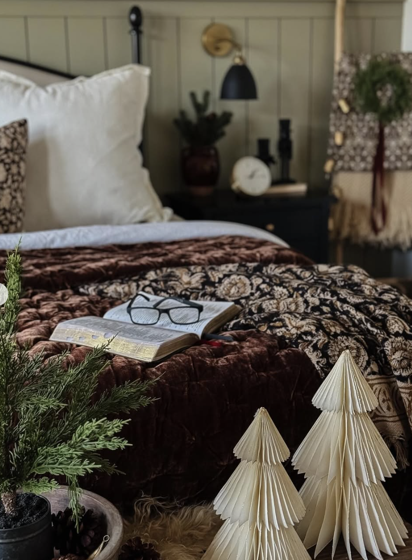 rustic farmhouse christmas bedroom with patterned bedding, paper christmas trees, and warm vintage decor