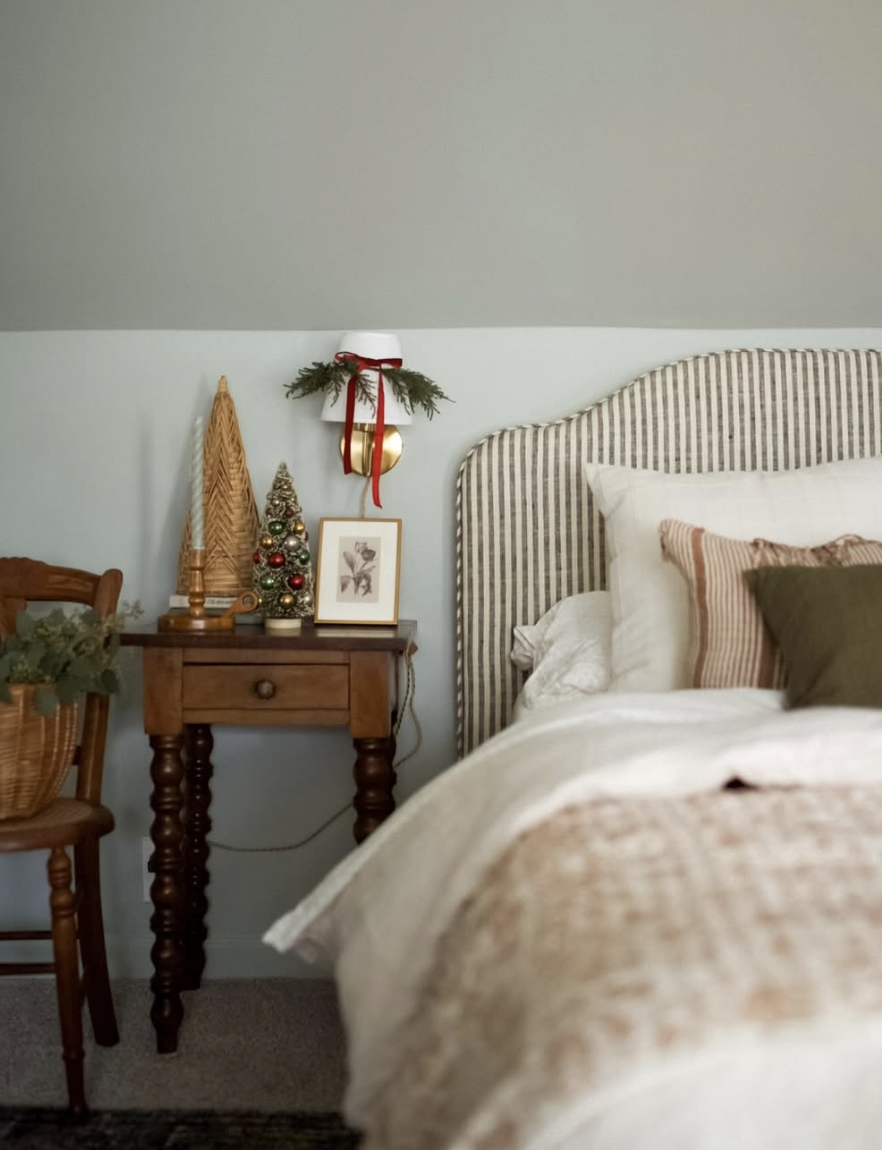 rustic farmhouse christmas bedroom with striped headboard, small tabletop tree, and cozy neutral bedding