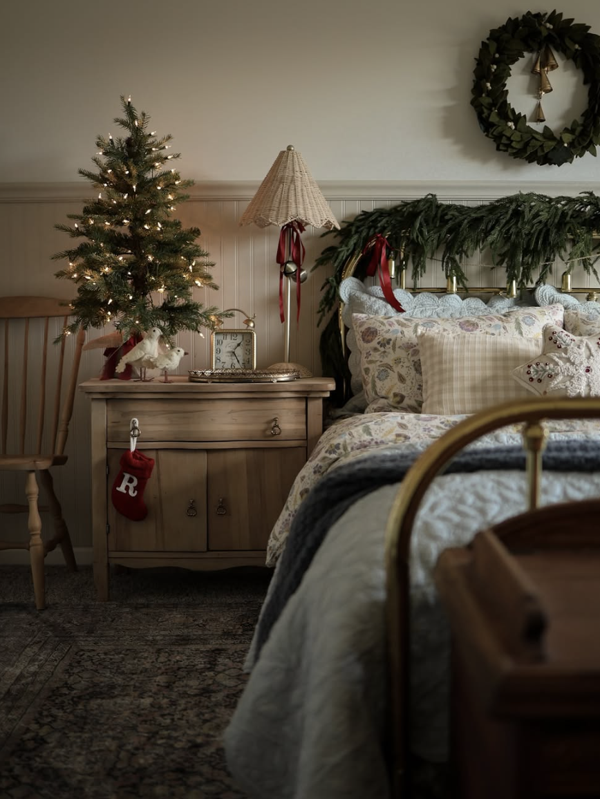 rustic farmhouse christmas bedroom with small christmas tree, brass bed frame, and greenery garland
