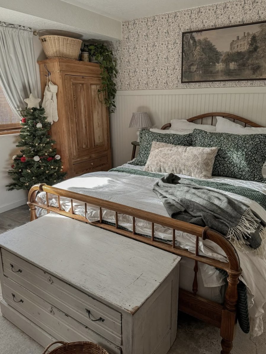 rustic farmhouse christmas bedroom with small christmas tree, green bedding, and vintage wood furniture