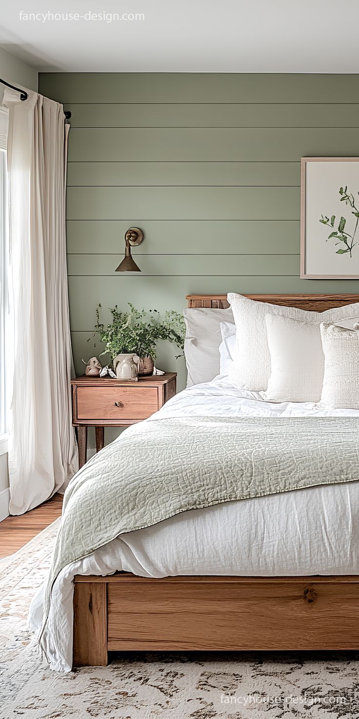 Bedroom with sage green horizontal shiplap accent wall, warm wood furniture, white bedding, and brass sconce lighting.