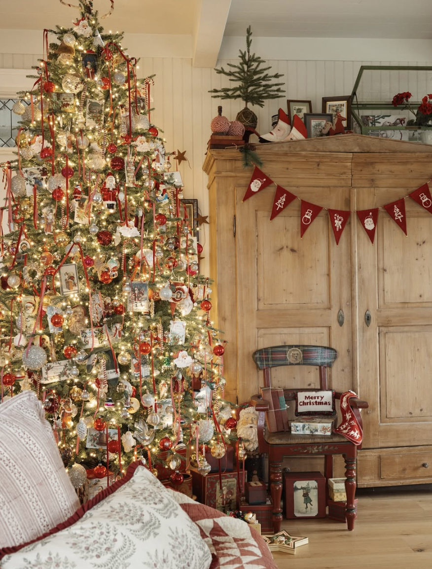 rustic farmhouse Christmas tree with red ribbons, vintage ornaments, and Santa decorations in cozy country living room with warm holiday lighting