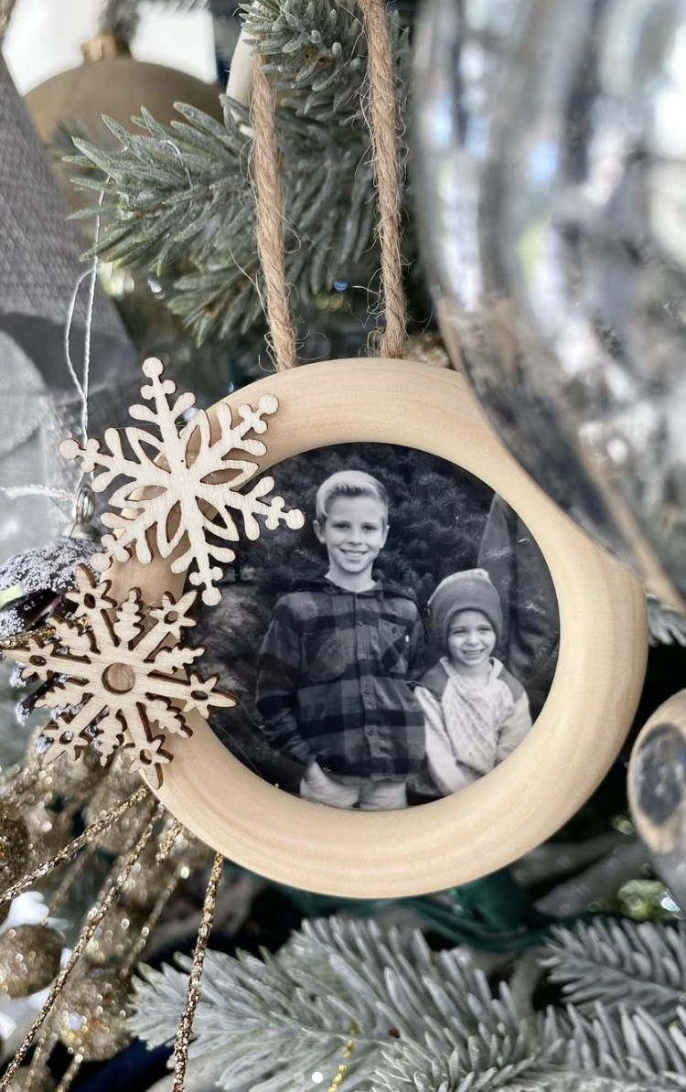 DIY wooden frame snowflake photo ornament with black and white family photo, natural wood frame, and decorative wooden snowflakes hanging on a Christmas tree