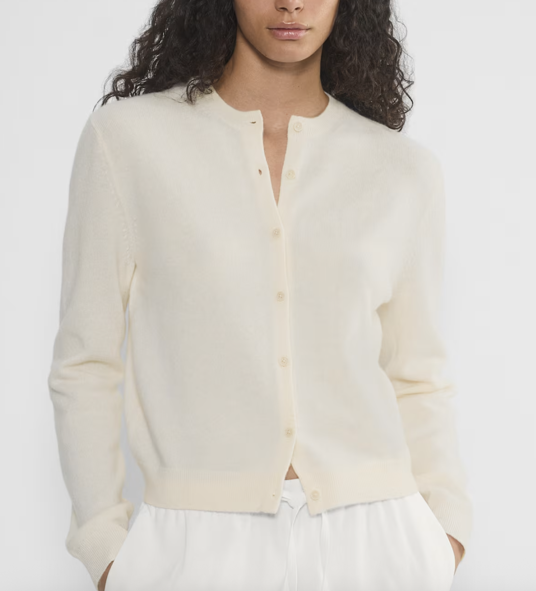 Woman wearing a cream Aritzia Bare Cashmere crew cardigan with button front.