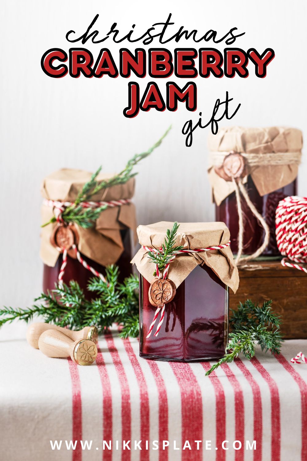 Jars of homemade cranberry jam wrapped in kraft paper and tied with red and white string - a festive homemade homemaker gift idea for Christmas.