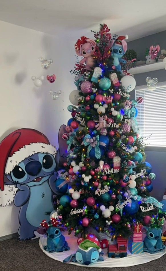Bright Lilo and Stitch Christmas tree decorated with pink, teal, and blue ornaments, Stitch and Angel plush toys, character cutouts, and vibrant holiday accents.