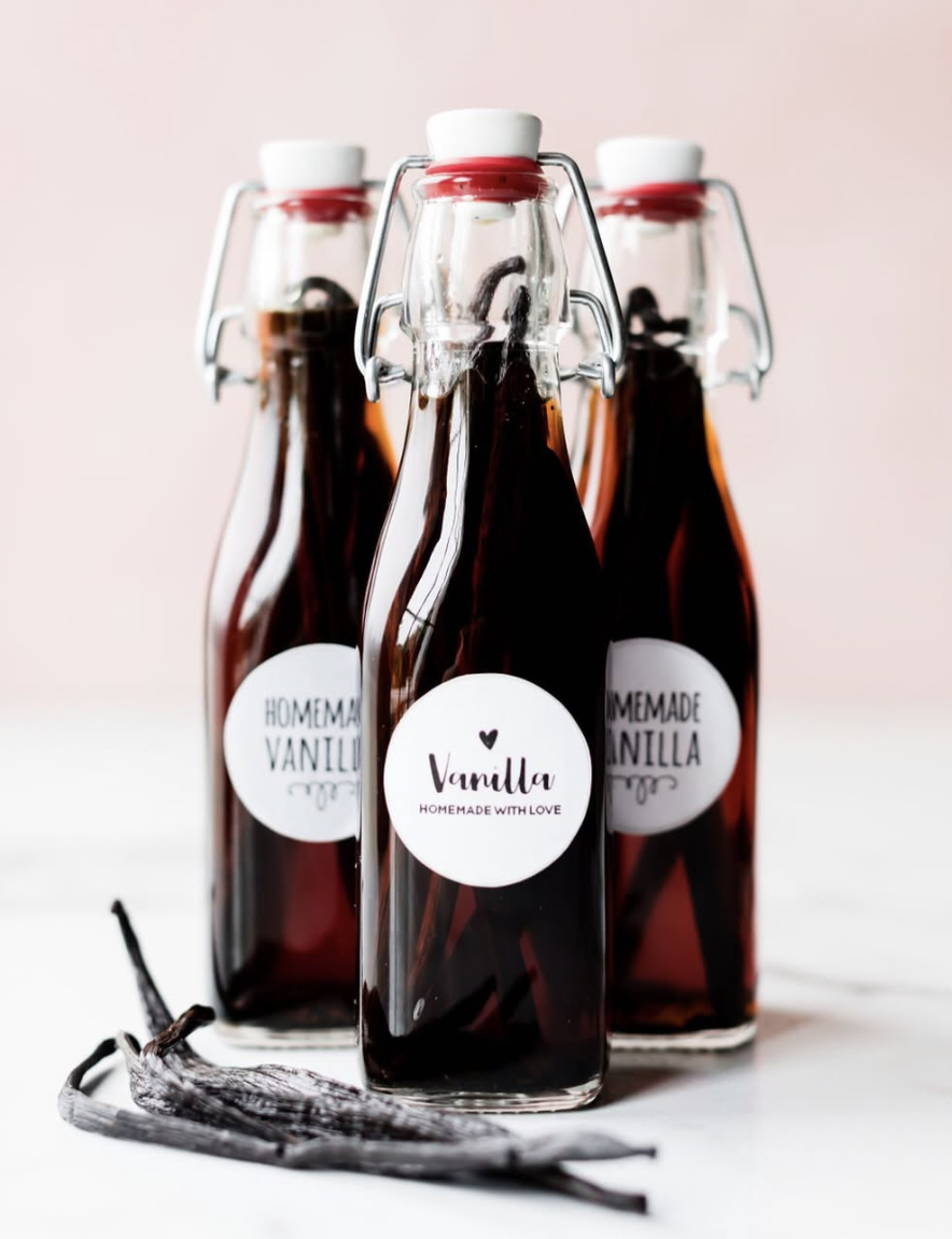 Glass bottles of homemade vanilla extract with vanilla beans inside - a thoughtful and easy homemade homemaker gift idea for Christmas.