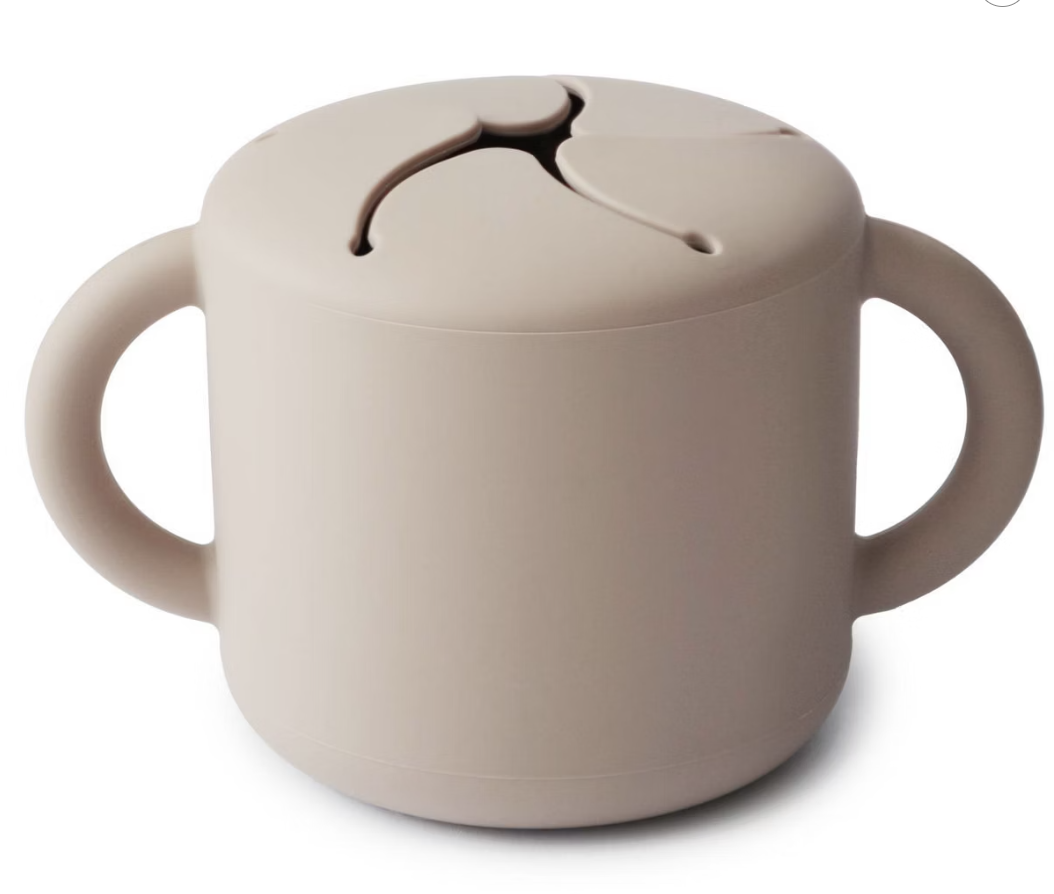beige Mushie silicone snack cup with two handles and soft lid non-toxic baby feeding accessory