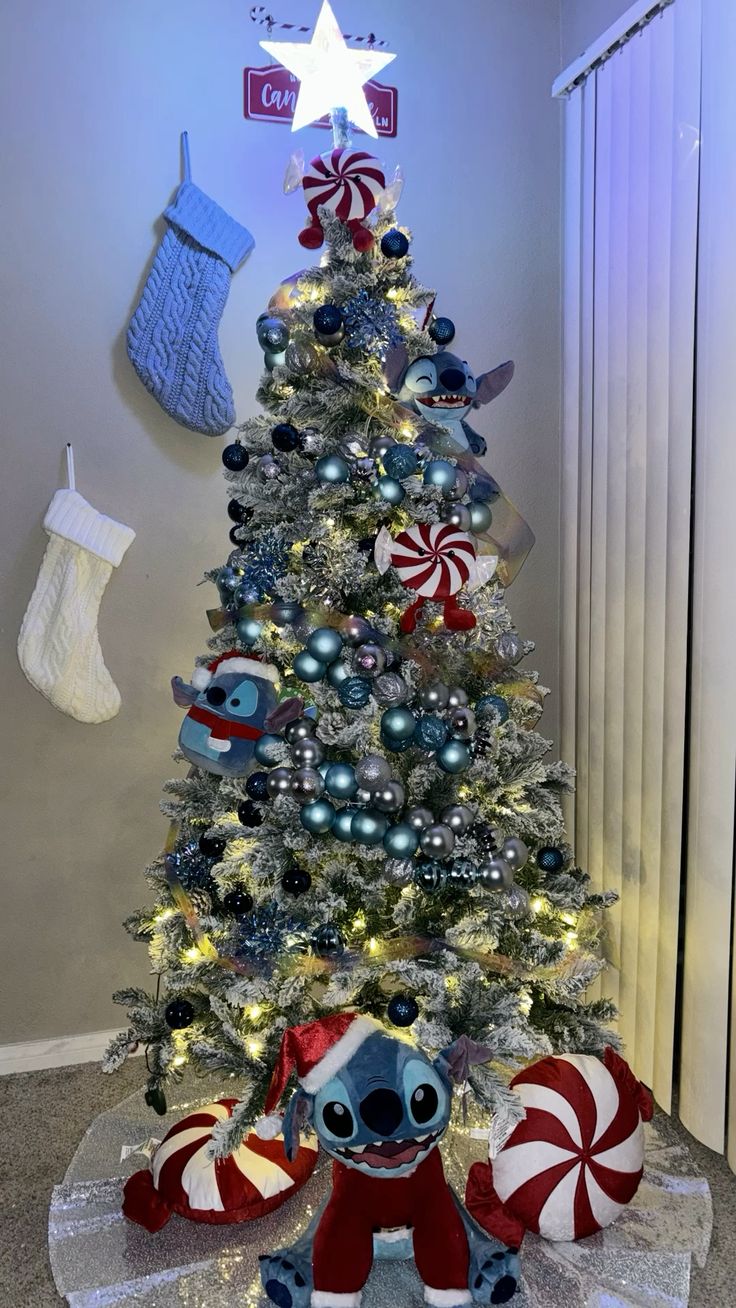 Flocked Christmas tree decorated with blue and silver ornaments, peppermint accents, Stitch plush toys, and glowing lights for a cute Lilo & Stitch holiday theme.