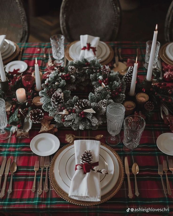 Ralph Lauren-inspired Christmas table setting with a red tartan tablecloth, frosted pine wreath centerpiece, crystal glassware, gold-rimmed plates, and pinecone napkin rings for a refined, classic holiday dining look.