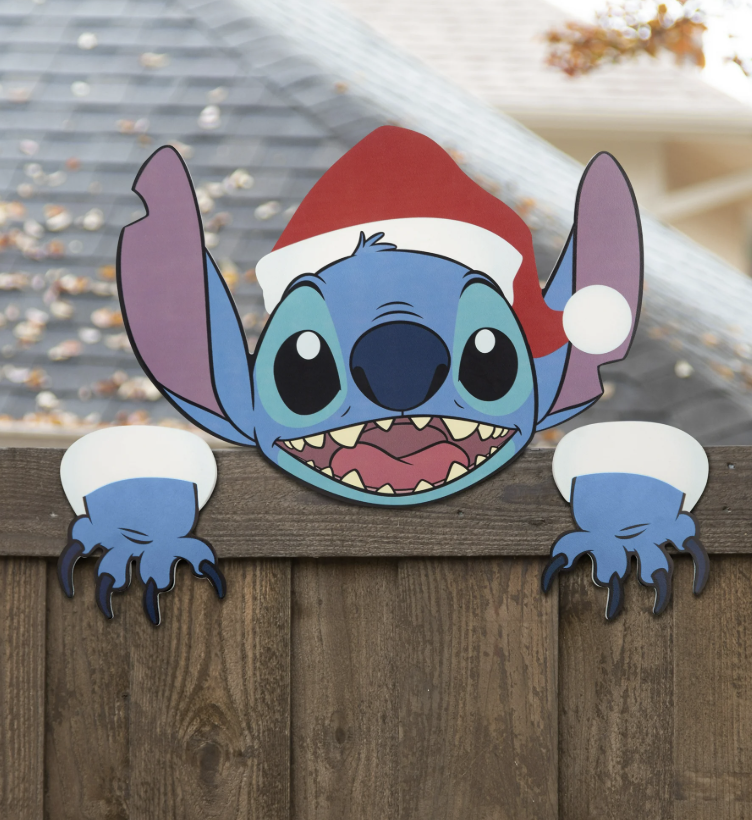 Outdoor Stitch fence sitter decoration featuring Stitch in a Santa hat peeking playfully over a wooden fence.