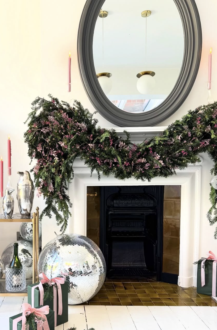 Wicked-inspired Christmas mantel decorated with pink and green glitter cone trees, pine greenery, pinecones, and ornaments.