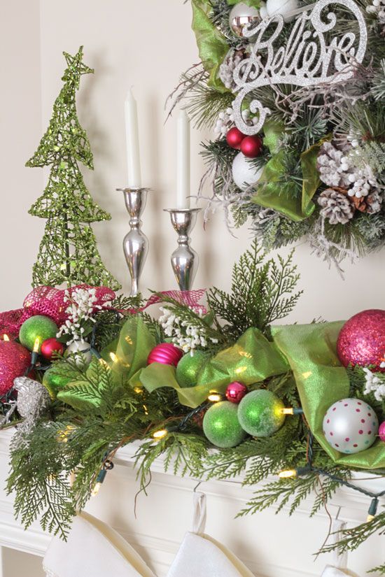 Wicked-inspired Christmas mantel decorated with green and pink ornaments, sparkly ribbon, pine greenery, and silver candlesticks.