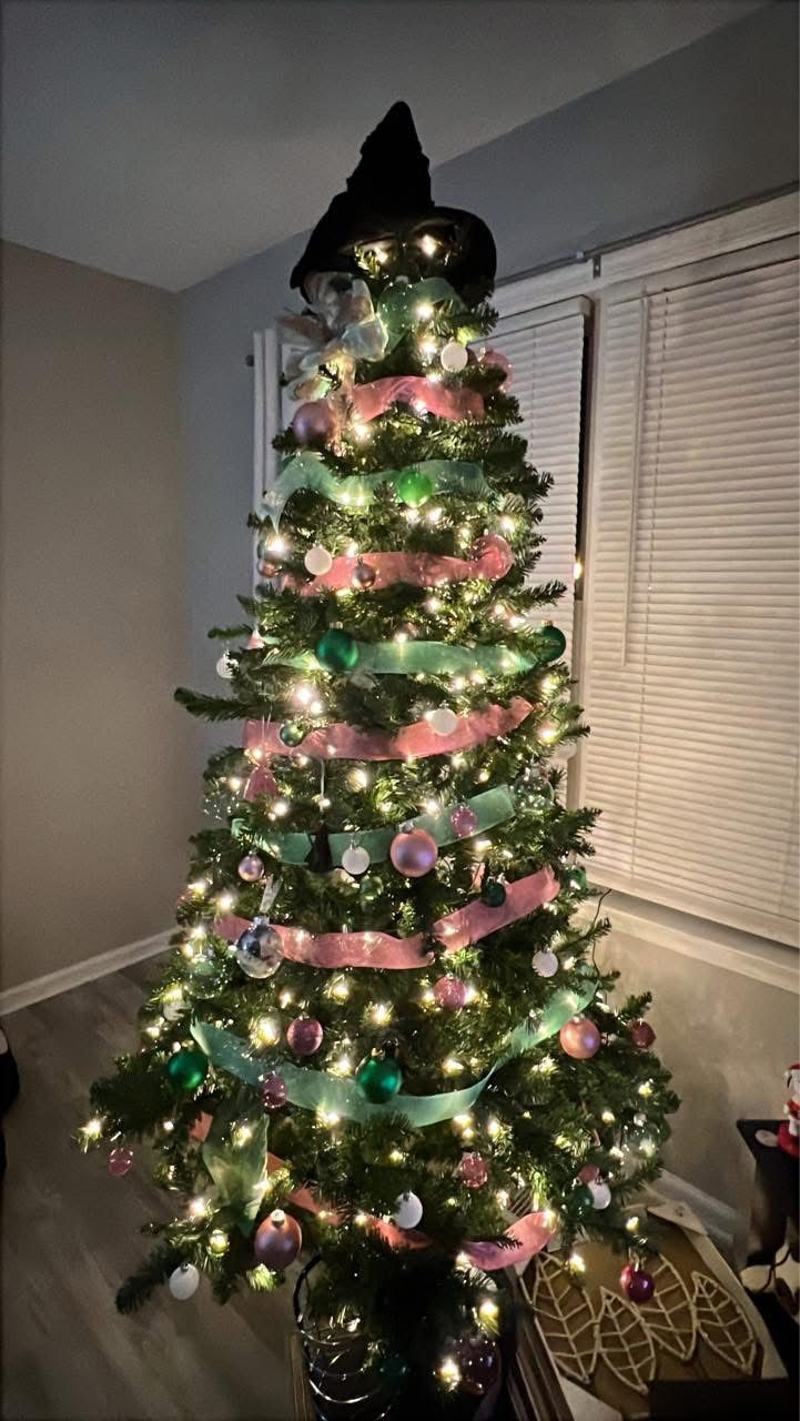 Wicked Christmas tree decorated with pink and green ribbon, glowing lights, and a witch hat topper for a fun and magical holiday look.