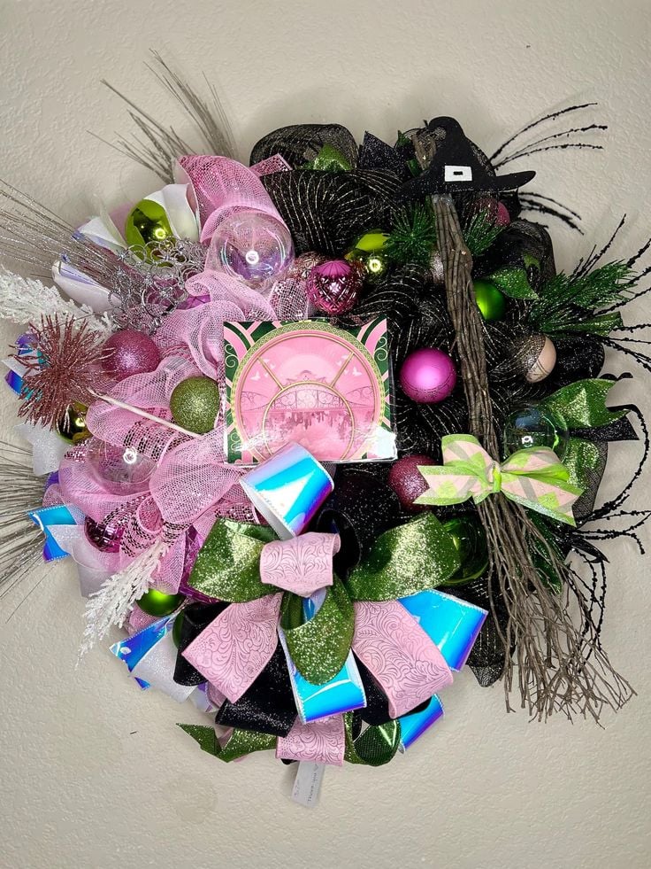 Wicked Christmas wreath decorated with pink, green, and black ribbons, glitter ornaments, and a witch hat accent for a magical holiday look.
