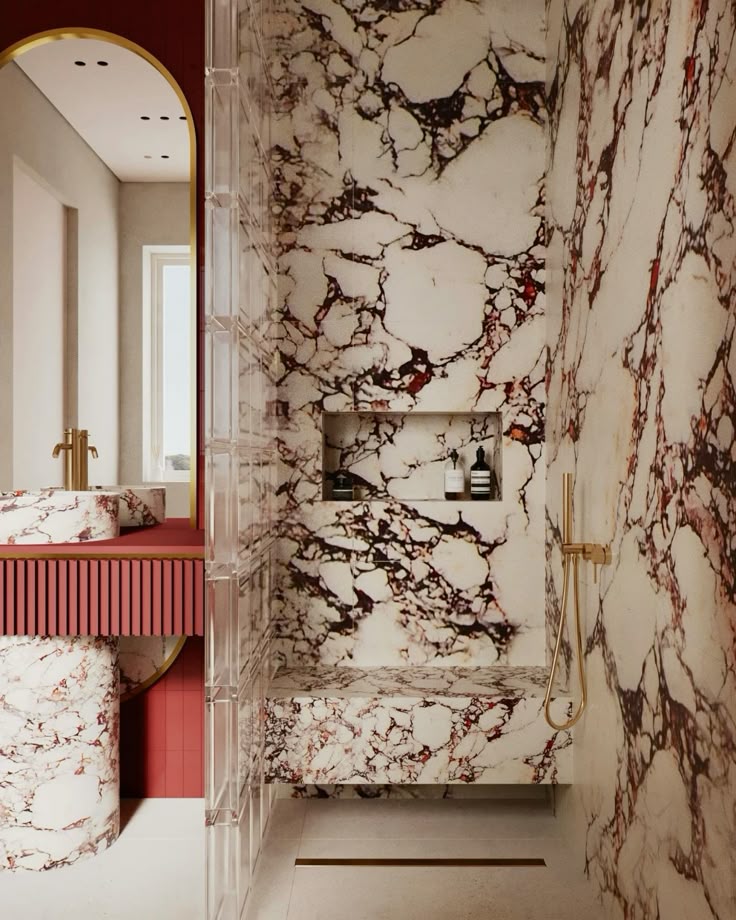 A luxurious bathroom showcasing a floor-to-ceiling red and white marble shower with a built-in bench, brass fixtures, glass block partition, and a matching marble vanity.
