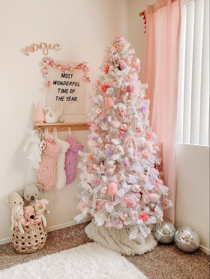 Pastel pink Christmas tree decorated with soft ornaments, chunky stockings, and cozy kids' room holiday decor.