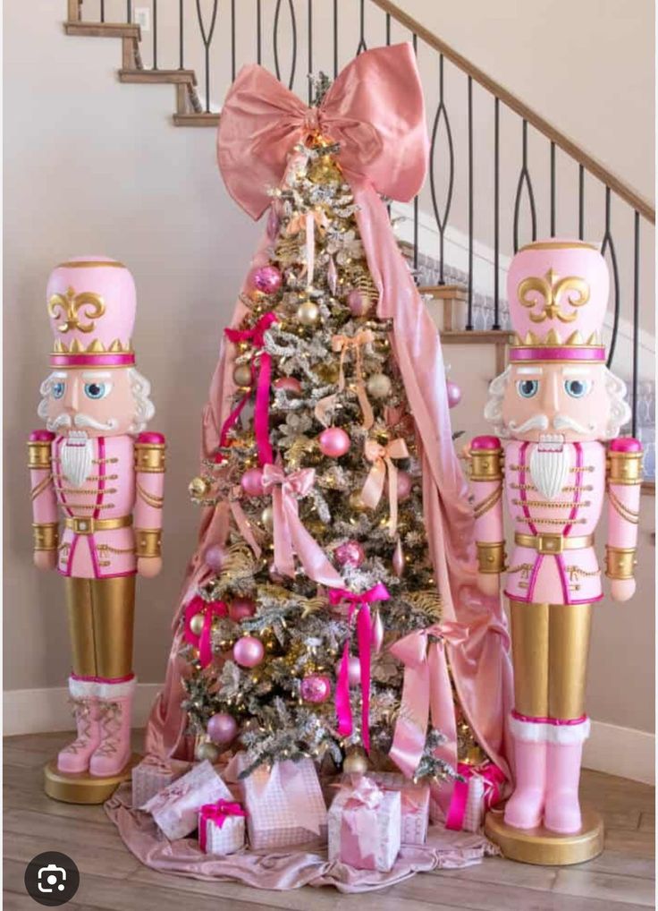 Christmas tree decorated with pink ornaments and ribbons, flanked by two oversized pink nutcrackers and wrapped in a large blush bow.