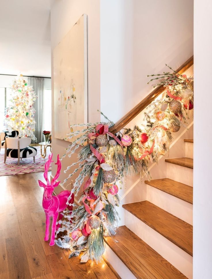 Staircase decorated with a lush pink Christmas garland, glitter ornaments, ribbon accents, and a bright pink reindeer for a bold holiday look.