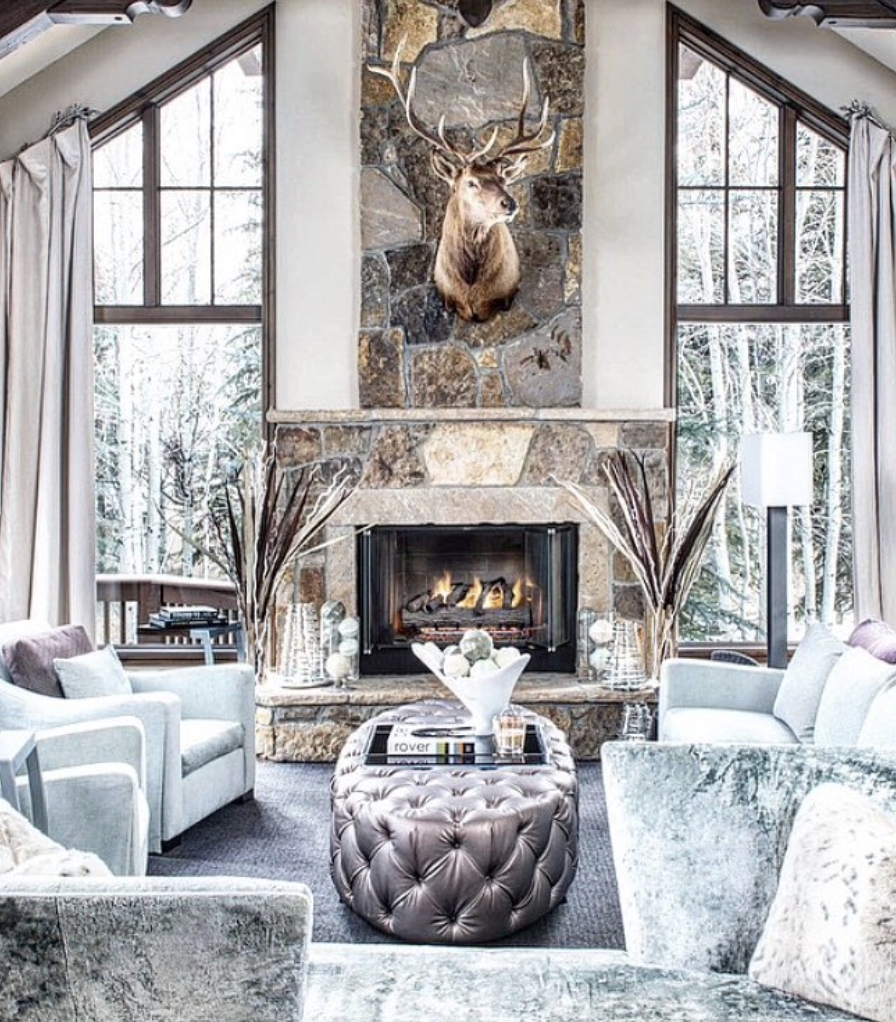 Rustic cabin deer aesthetic living room with a stone fireplace, neutral seating, and a deer wall accent