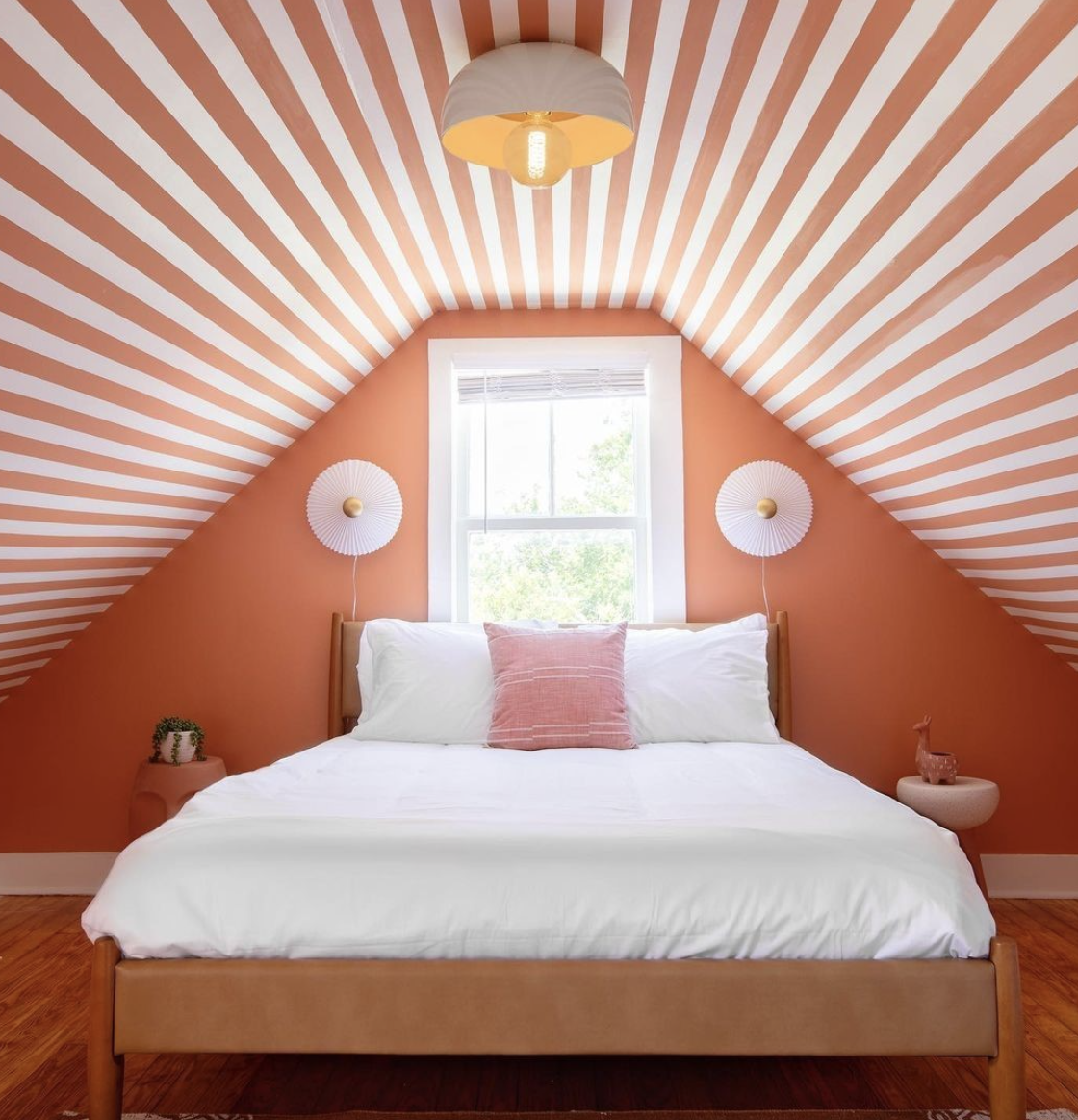 Bold striped ceiling bedroom featuring orange and white stripes on a sloped ceiling with a warm, modern design.