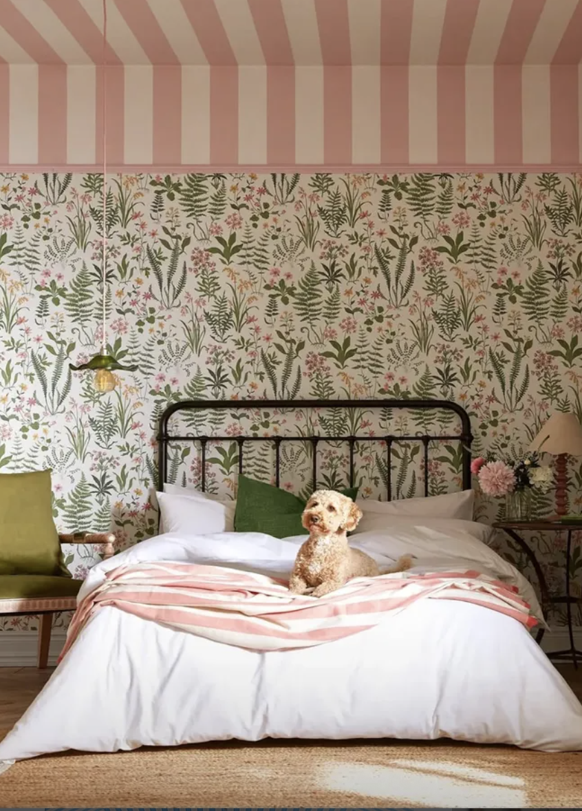 Bold striped ceiling bedroom featuring pink and white ceiling stripes paired with floral wallpaper and layered bedding.