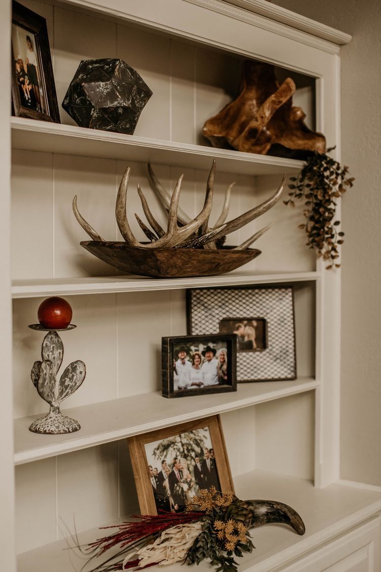 Cozy deer aesthetic shelf decor featuring antlers, framed photos, natural textures, and warm neutral styling