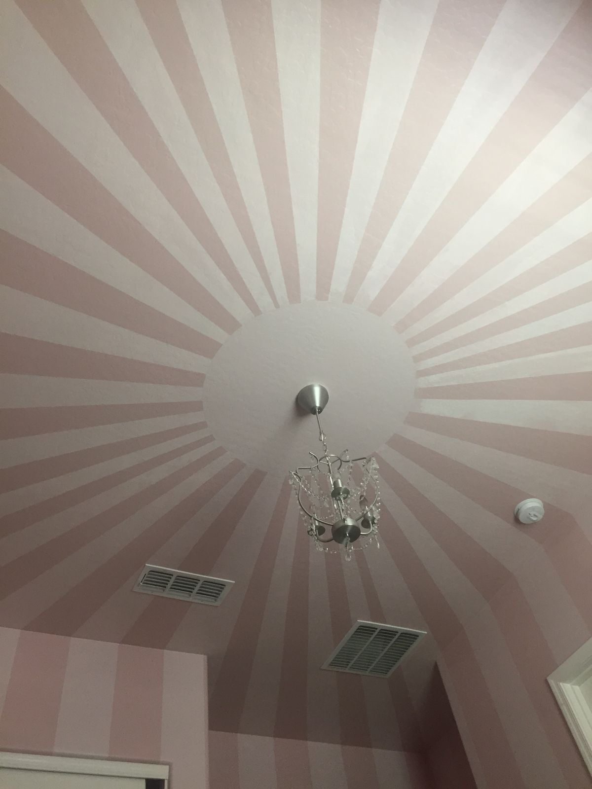 Kids striped ceiling bedroom featuring a pink and white sunburst striped ceiling with a chandelier light fixture.