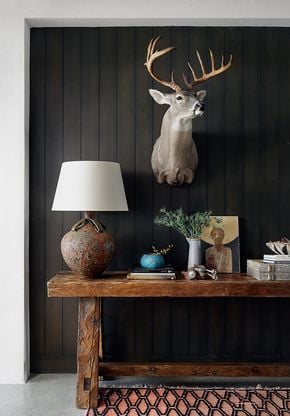 Minimal deer aesthetic console table featuring a mounted deer accent, dark paneled wall, and simple rustic decor