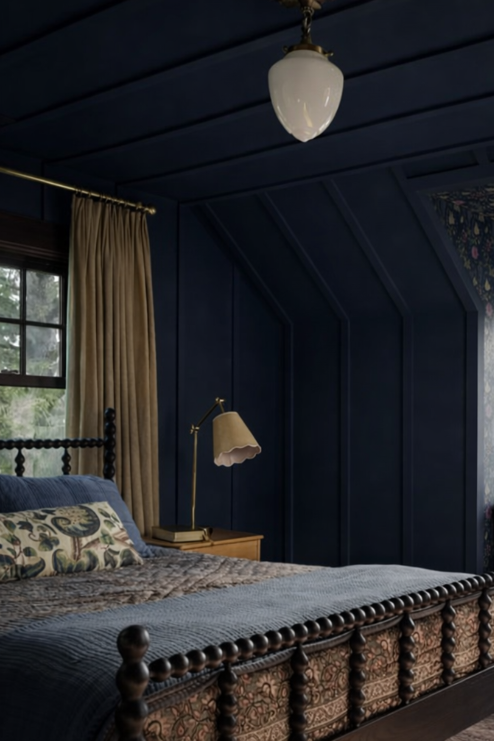 Navy blue attic bedroom with sloped ceilings, spindle bed, built-in window seat, floral wallpaper, and warm neutral accents