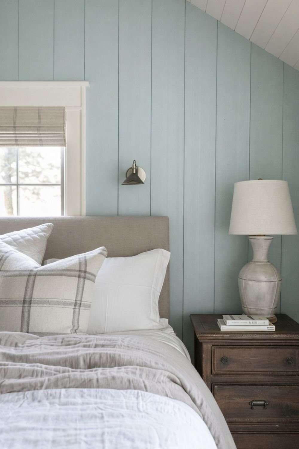 Bedroom with robin's egg blue shiplap wall, neutral upholstered headboard, white bedding, and wooden nightstand