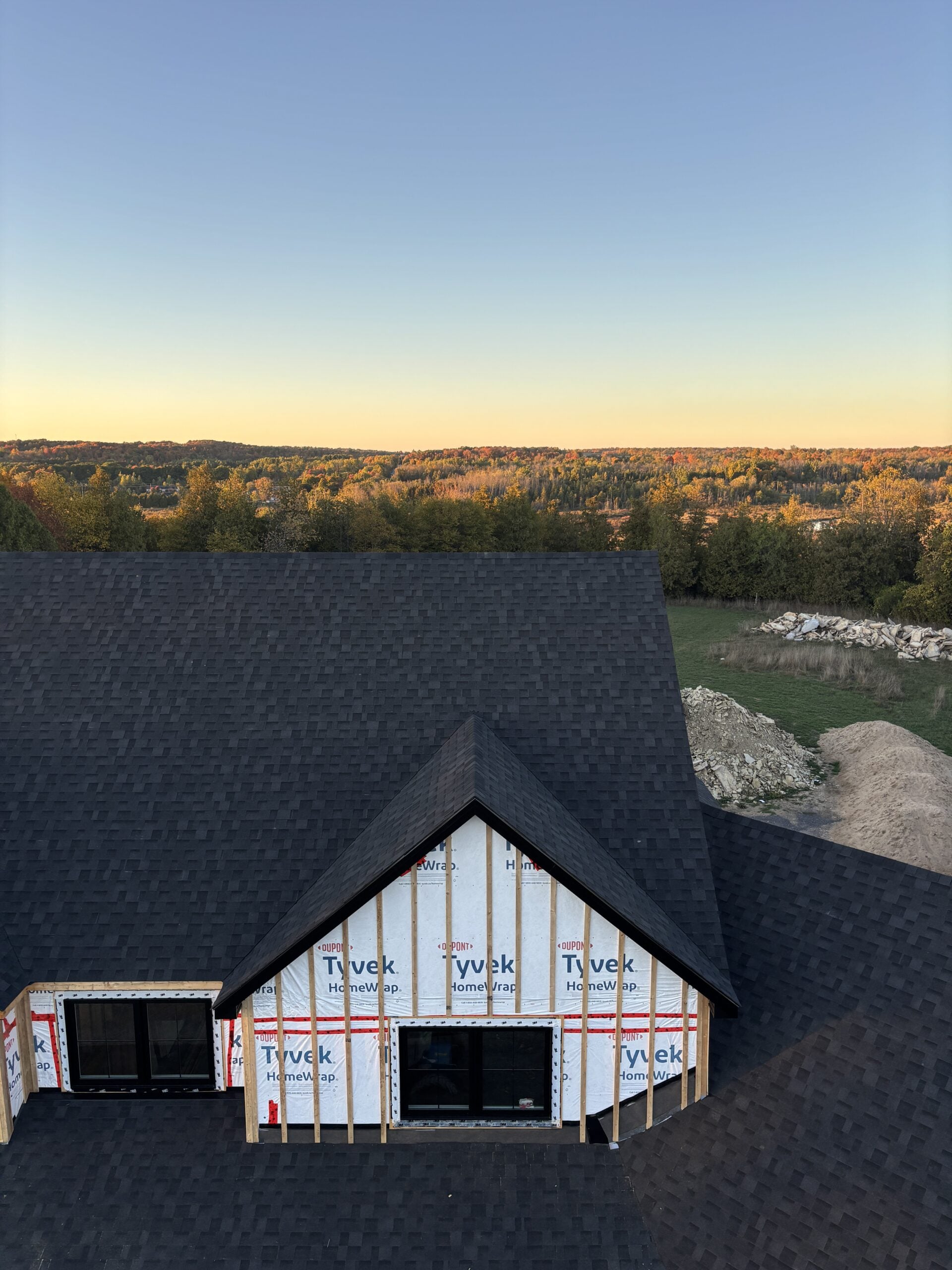 Black asphalt shingle roof installed on our modern farmhouse build, featuring steep gables and black windows on a rural Ontario property.