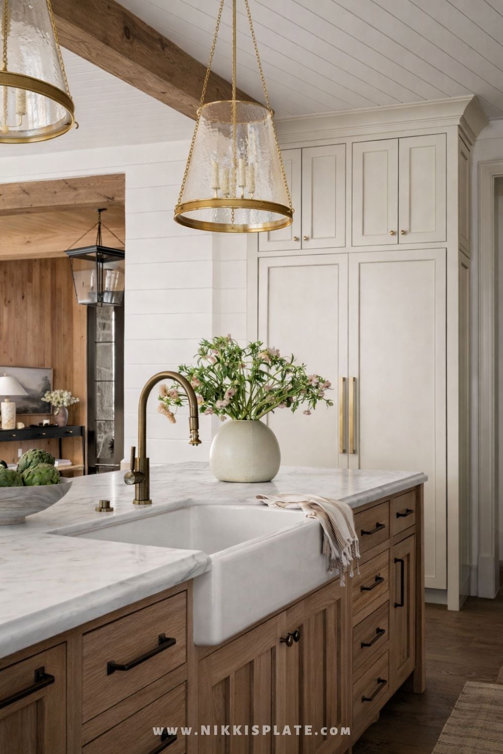 Textured glass lantern pendant light hanging above a farmhouse kitchen island with a white apron-front sink and rustic wood cabinetry.