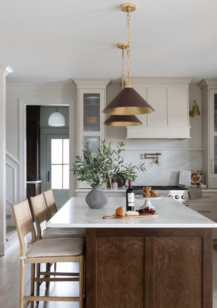 Farmhouse kitchen with a walnut island, white countertop, brass pendant light, and leather island chairs.
